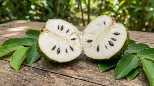 Soursop graviola fruit halved on wooden table with tropical green leaves - natural source of acetogenins