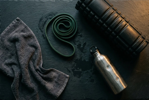 Foam roller and gym equipment on dark surface — muscle function support with PURETREX Magnesium Glycinate